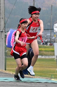 女子・三原の４区富山沙葵選手（右）からたすきを受け取り走りだす５区橋本青空選手＝豊岡市日高町（撮影・秋山亮太）