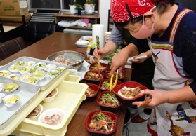 猪肉のメニューを盛り付ける伊加利地区の主婦ら＝伊加利地区公民館