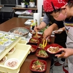 猪肉のメニューを盛り付ける伊加利地区の主婦ら＝伊加利地区公民館