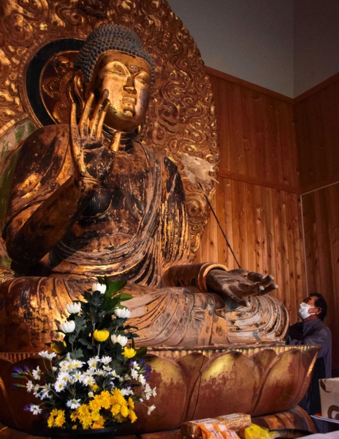 釈迦如来坐像に積もったほこりを落とす檀家ら＝淡路国分寺