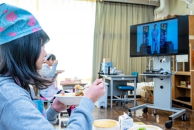住村竜市朗さんのビデオメッセージが流れる中、カレーライスを味わう児童ら＝塩田小学校（淡路市提供）