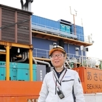 秋田県から帰港した台船「あさひ」を前に、笑顔を見せる関勝社長＝淡路市生穂新島