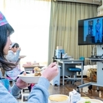 住村竜市朗さんのビデオメッセージが流れる中、カレーライスを味わう児童ら＝塩田小学校（淡路市提供）