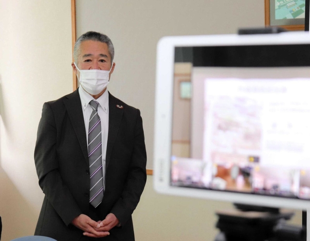 感染対策のため、タブレット端末（右）を通じて各教室の生徒に話す米山正幸さん＝三原中学校