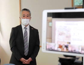 感染対策のため、タブレット端末（右）を通じて各教室の生徒に話す米山正幸さん＝三原中学校