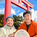 完成した藍染めのお守りを持つ根岸誠一さん（左）と、森の木ファームの生活支援員柳尚孝さん＝おのころ島神社