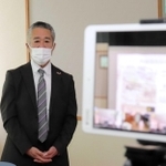 感染対策のため、タブレット端末（右）を通じて各教室の生徒に話す米山正幸さん＝三原中学校