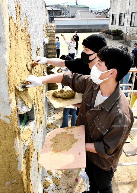 こてを手に土壁を塗る生徒たち＝近畿壁材工業