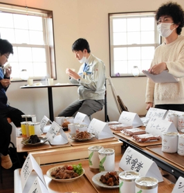 直売所関係者向けの試食会で説明する学生（右）＝洲本市五色町鳥飼浦