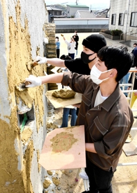 こてを手に土壁を塗る生徒たち＝近畿壁材工業