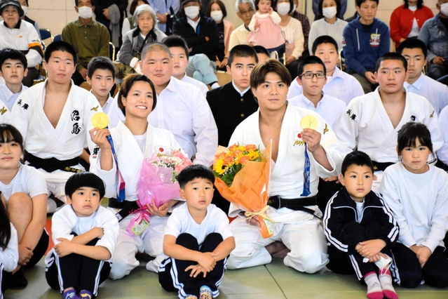 東京五輪の金メダルを手に、沼島の小中学生らと記念撮影する阿部一二三選手と詩選手＝南あわじ市沼島