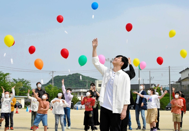 子どもたちと風船を空に飛ばす林部智史さん＝都志小学校