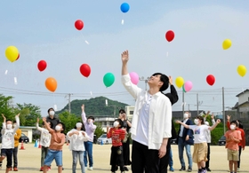 子どもたちと風船を空に飛ばす林部智史さん＝都志小学校