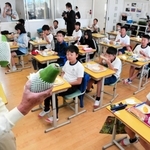 学校給食で青パパイアを味わった児童に話をする森久則さん＝２０２１年１０月、津名東小学校