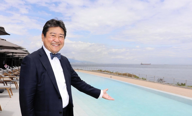 目玉の水着で入る温泉を指すアクアイグニス淡路島の古市尚社長＝淡路市夢舞台