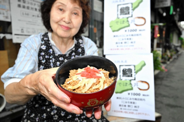 淡路島の旬の味覚を詰め込んだ「鱧そぼろ丼」と野口純子さん＝洲本市本町、レトロこみち