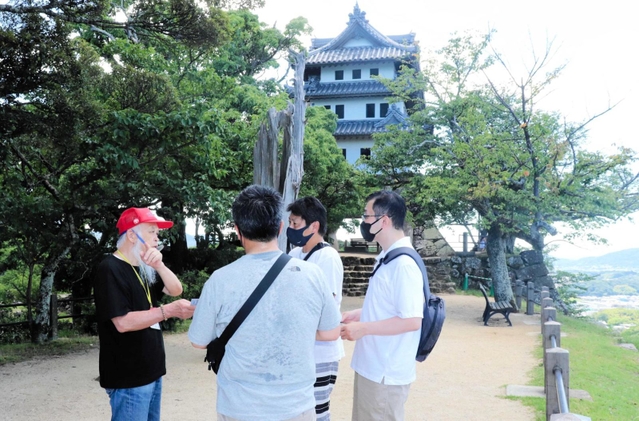 大阪湾と洲本市街を見下ろす本丸でガイドを務める「洲本城友の会」メンバー（左）＝洲本市小路谷
