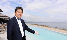 目玉の水着で入る温泉を指すアクアイグニス淡路島の古市尚社長＝淡路市夢舞台