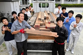 来田材木店の土井章史さん（手前左）から木材を受け取る石井滉志郎さん（同右）ら建築研究部員＝東播工業高校
