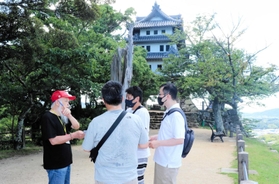 大阪湾と洲本市街を見下ろす本丸でガイドを務める「洲本城友の会」メンバー（左）＝洲本市小路谷