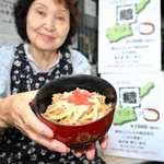 淡路島の旬の味覚を詰め込んだ「鱧そぼろ丼」と野口純子さん＝洲本市本町、レトロこみち