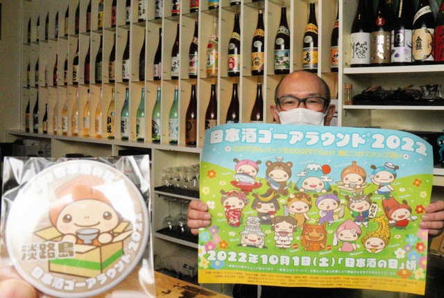 ゴーアラウンド用の缶バッジと、ポスターを持つ矢野さん＝洲本市本町４