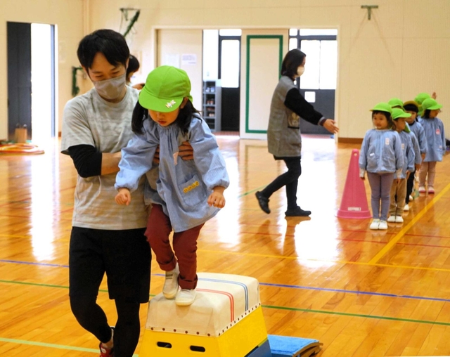 跳び箱に慣れる練習で園児に手を添える沖口誠さん＝由良小（洲本市提供）