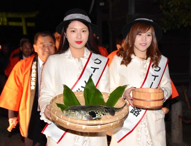 ふぐ供養と献湯神事を行うため、フグと温泉の湯を手に神社に向かうクイーン淡路たち＝洲本八幡神社