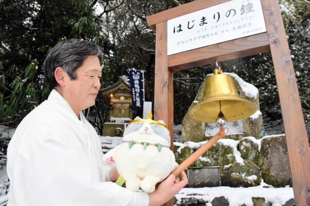 境内に設置した「はじまりの鐘」を鳴らす奥本憲治宮司と主人公「マル」のぬいぐるみ＝諭鶴羽神社