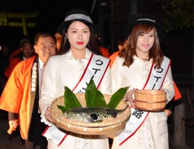 ふぐ供養と献湯神事を行うため、フグと温泉の湯を手に神社に向かうクイーン淡路たち＝洲本八幡神社