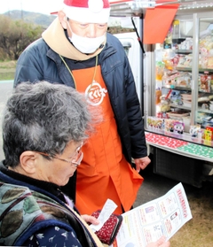 移動スーパーの販売員から、火災予防の要点を記したチラシを受け取る高齢者＝洲本市五色町広石下
