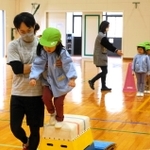 跳び箱に慣れる練習で園児に手を添える沖口誠さん＝由良小（洲本市提供）