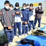 ブルーシートの両端を固定した簡易寝袋を体験する生徒＝南淡中学校