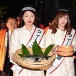 ふぐ供養と献湯神事を行うため、フグと温泉の湯を手に神社に向かうクイーン淡路たち＝洲本八幡神社
