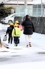 保護者に付き添われて雪道を通学する子どもたち＝淡路市志筑