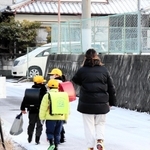 保護者に付き添われて雪道を通学する子どもたち＝淡路市志筑