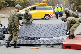 土のうとプラスチック板で段差を埋める自衛隊員＝洲本市納