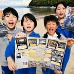 ロケ地マップを手にする、エキストラで撮影に参加した子どもたち＝大浜海岸