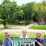 志知城跡（後方）の駐車場として自宅前のスペースを提供した藤江武弘さん（中央）ら＝南あわじ市志知