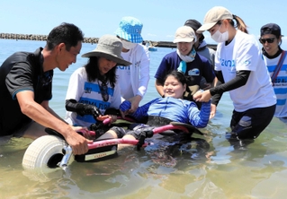 水陸両用車いすに乗って海につかる赤松桃果さん＝阿万海水浴場