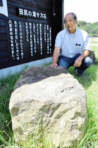 田尻の源サのひ孫山形収司さんと、運んだとされる巨石＝南あわじ市阿万塩屋町