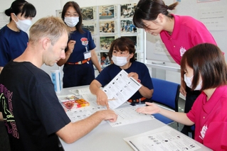 指でボードを示して外国人と意思疎通する消防団と防災女子のメンバー＝淡路市防災あんしんセンター