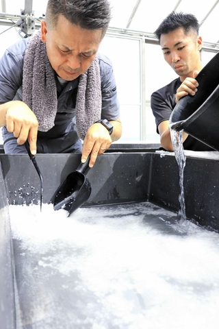 海水を蒸発させて塩を作る山下勤也さん（左）と濵野雄輝さん＝淡路市釜口