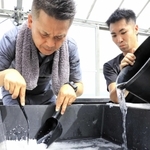 海水を蒸発させて塩を作る山下勤也さん（左）と濵野雄輝さん＝淡路市釜口