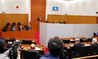 議場での証人尋問。証人が見えないようついたてが設けられた＝洲本市役所