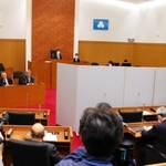 議場での証人尋問。証人が見えないようついたてが設けられた＝洲本市役所