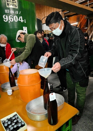 搾りたての酒を瓶詰めする参加者ら＝千年一酒造