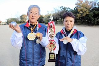 全国大会の優勝トロフィーとメダルを掲げる西谷信昭さん（左）と洋子さん＝淡路市生穂新島