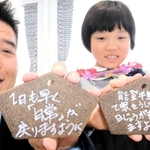 被災地への応援メッセージを書いた絵馬を持つ参加者＝淡路市野島平林