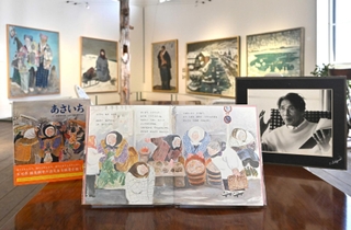 復刊された絵本「あさいち」。作者大石可久也さんの写真（右）と並ぶ＝アート山大石可久也美術館
